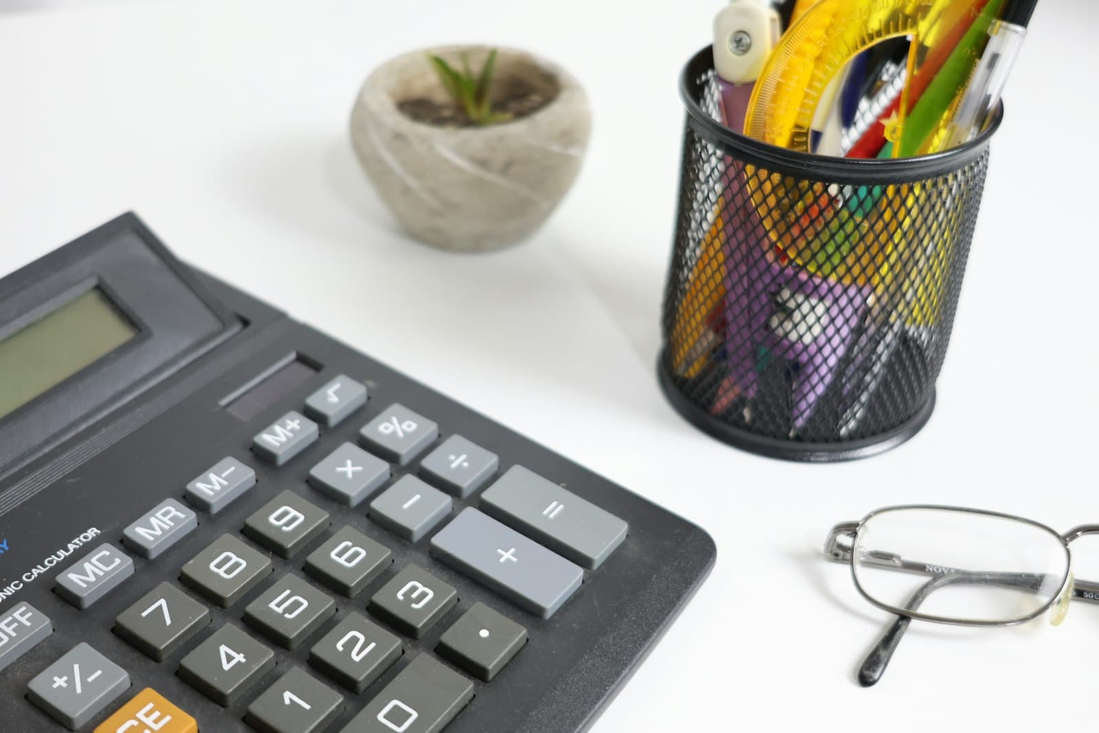 A calculator, glasses and stationery on a desk