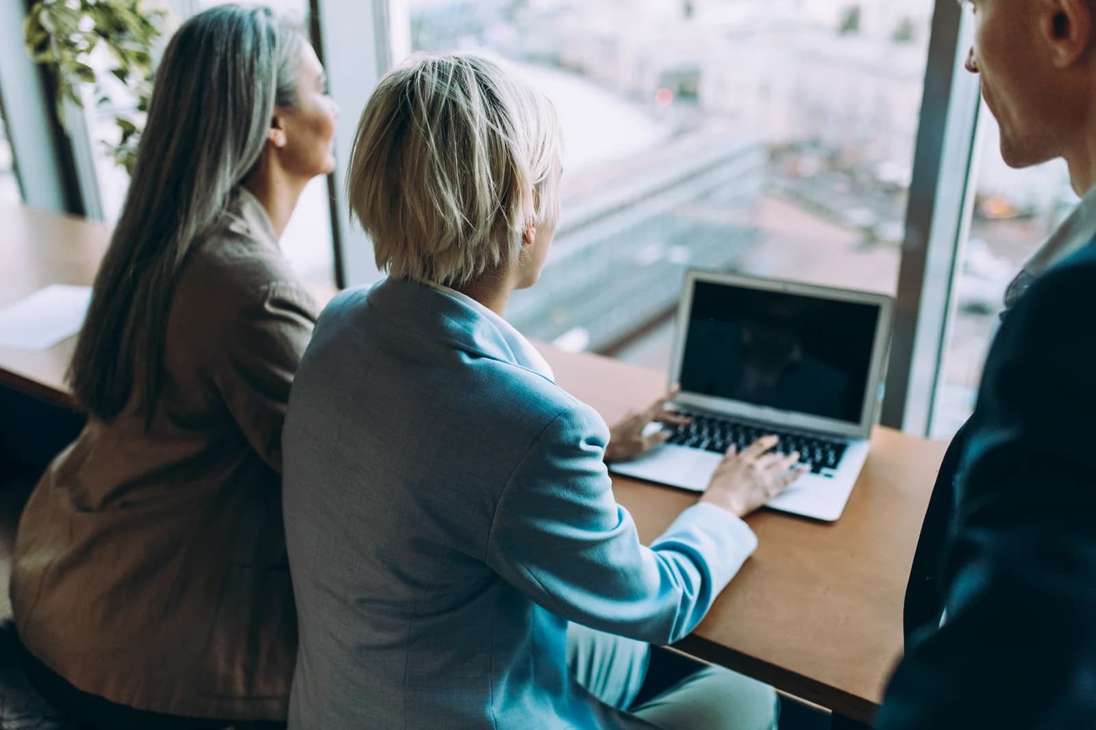 Colleagues working together on a laptop beside an office window