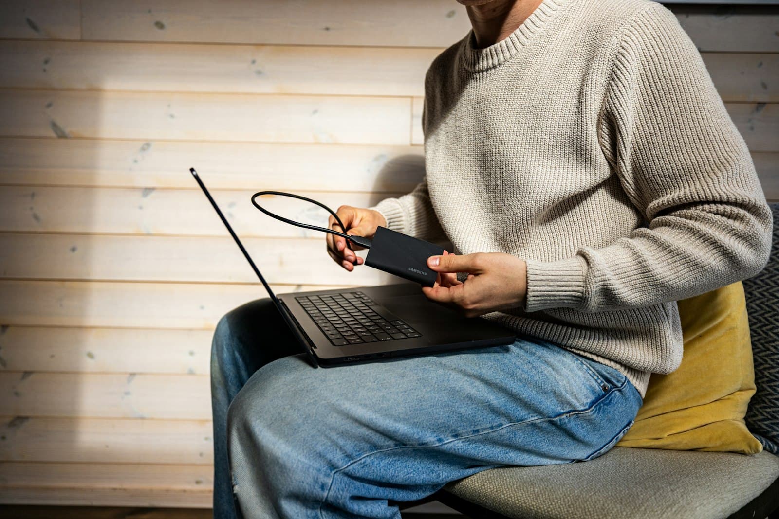 A person connecting an external drive to a laptop