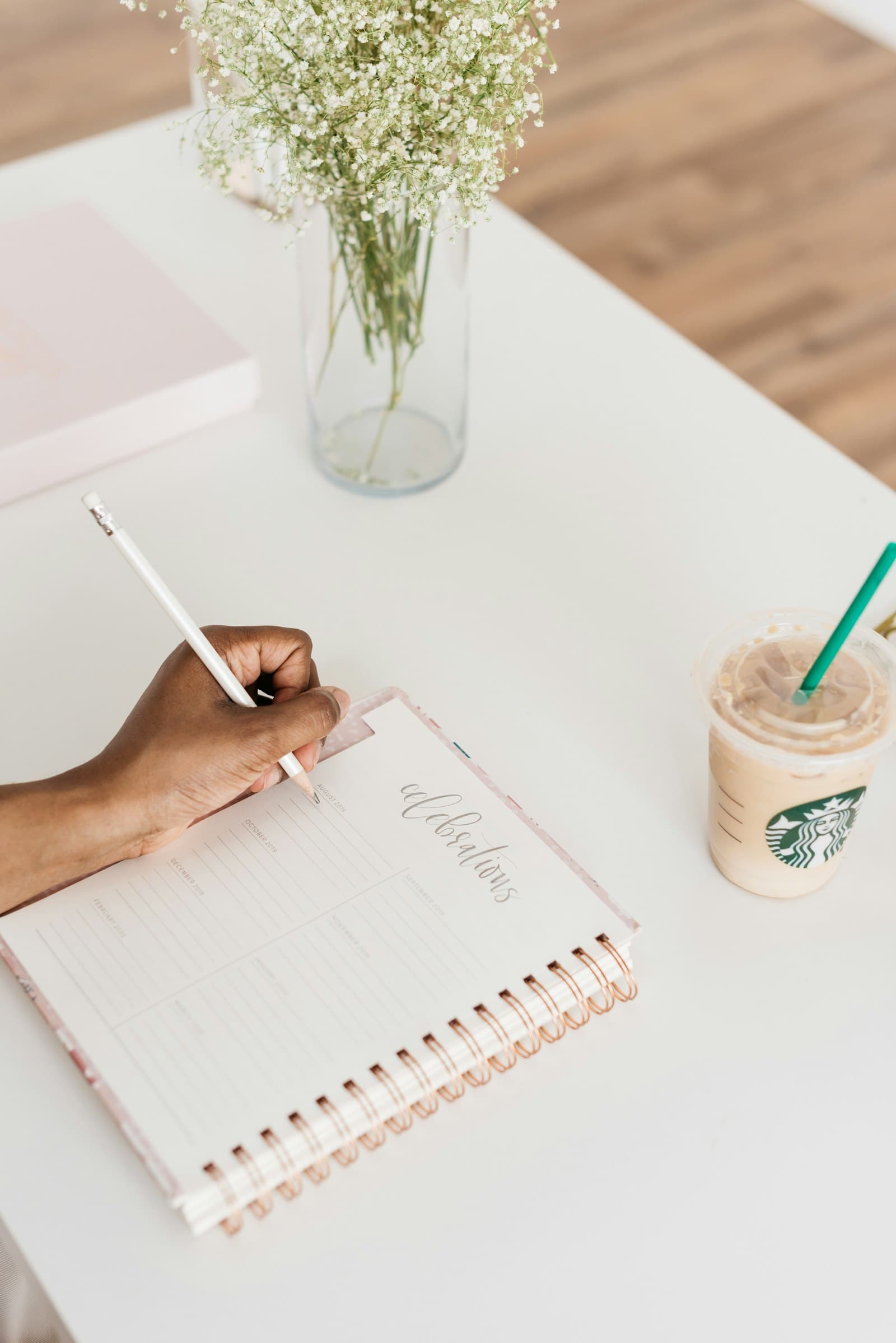 A hand writing in a planner at a desk
