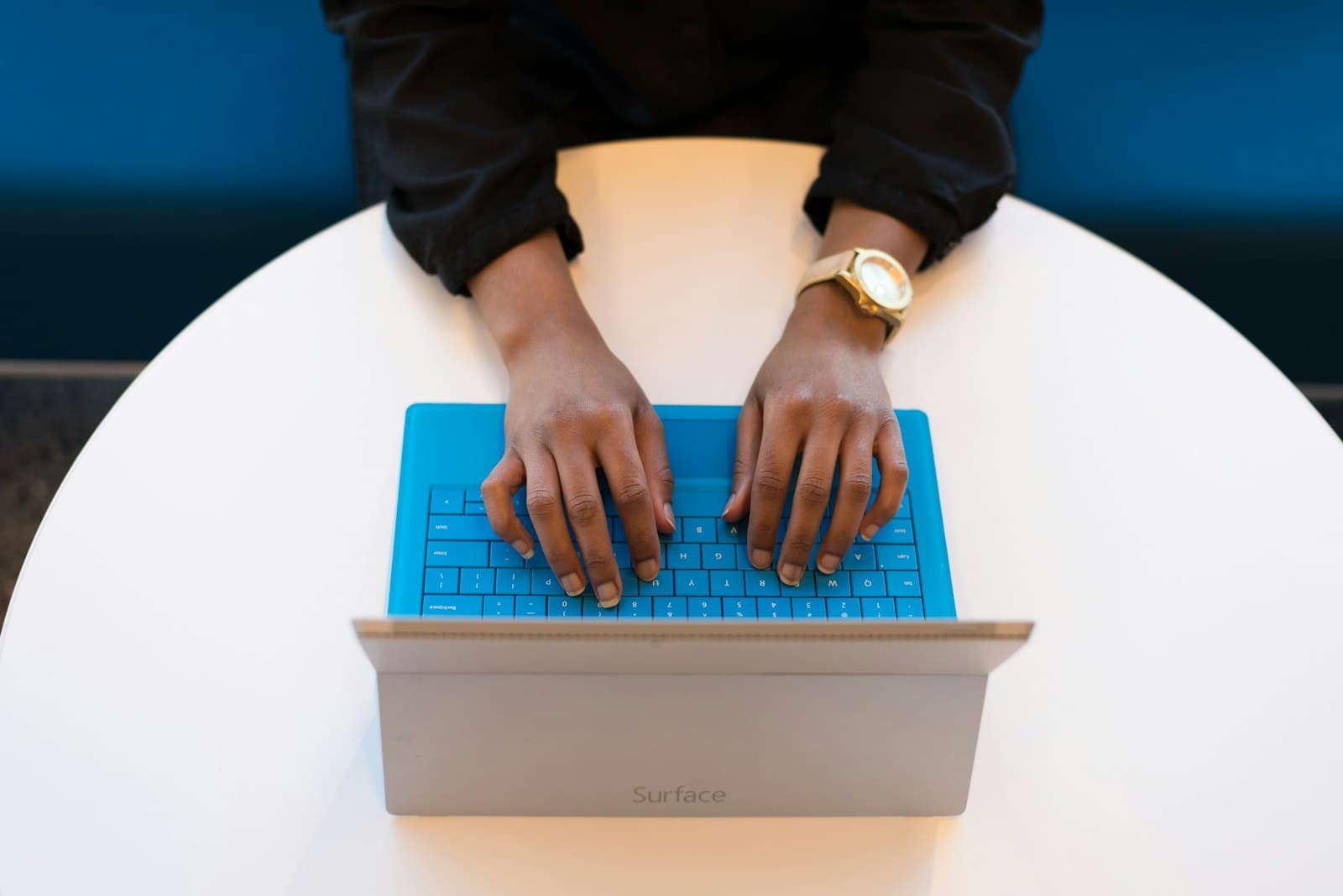Hands typing on a tablet computer with a blue keyboard